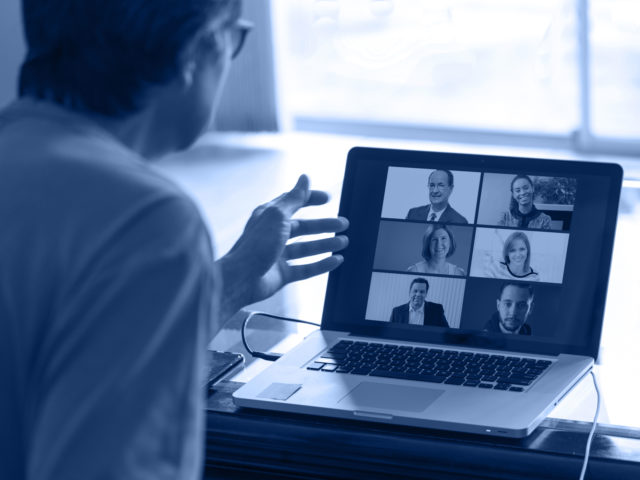 man speaking to people in a virtual meeting while teleworking