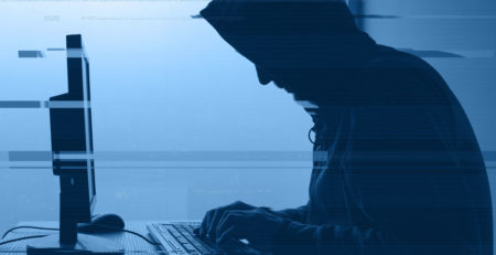 scary hacker in front of a computer with a blue overlay