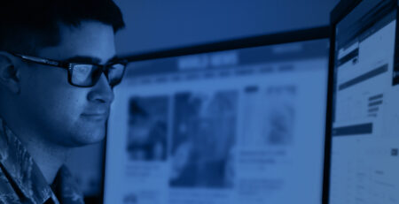 man with glasses looking at a computer screen with blue overlay