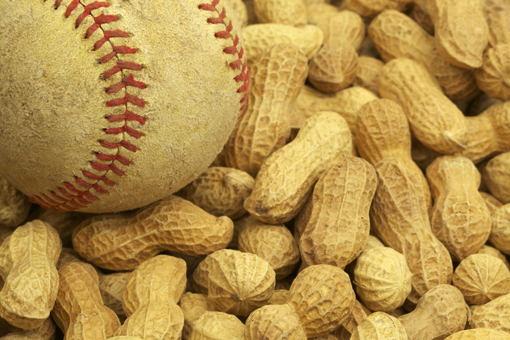 An image of a baseball settled atop a pile of whole peanuts. 